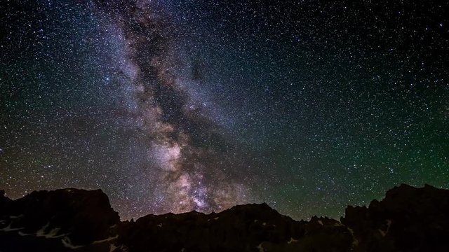 The outstanding beauty of the Milky Way and the starry sky beyond dramatic mountain ridge, captured at high altitude in summertime on the Italian Alps. Time Lapse 4k video.