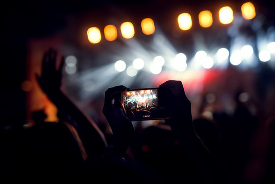 Photographing a live act at a concert with a smart phone.
