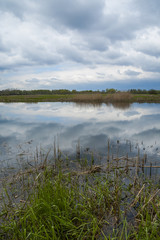 Quiet river, clouds reflected in the calm water depths. Spring.