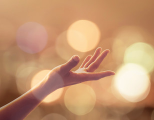 Human palm reaching upward in midst of glowing gold candle lights bokeh, candlemas: Female women...