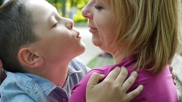 Mother kissing her son in the park, slow motion