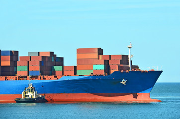 Fototapeta premium Tugboat assisting container cargo ship
