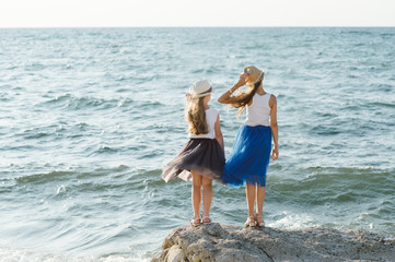 Fototapeta na wymiar Two little sisters on the rocky shores of the Black Sea