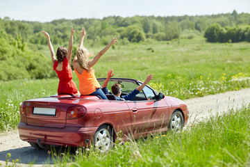 happy friends driving in cabriolet car at country