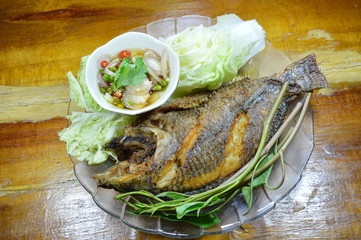 deep fried fish dipping chili fish sauce and vegetable on dish