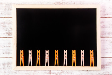 Blank blackboard and Orange clothes peg on wooden table.Template