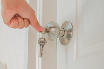 Hand hold door knob and open the white door with private key.