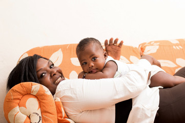 jeune femme souriante joue avec son bébé dans le canapé