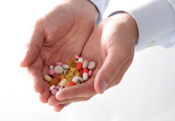 Male doctor holding a stack of many different pills