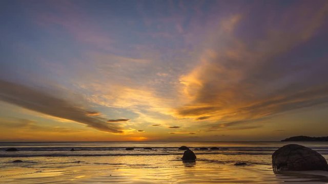 Vibrant Sunrise At Moeraki Boulders- Timelapse. Moeraki Boulders are a group of large spherical stones that have been exposed through shoreline erosion on Koekohe Beach near Moeraki. Pan Down