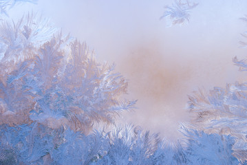 Fantastic abstract winter background (frost pattern on a window glass at the dawn), winter morning