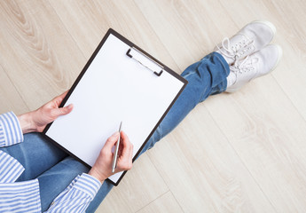 Unrecognizable woman making notes on a clipboard