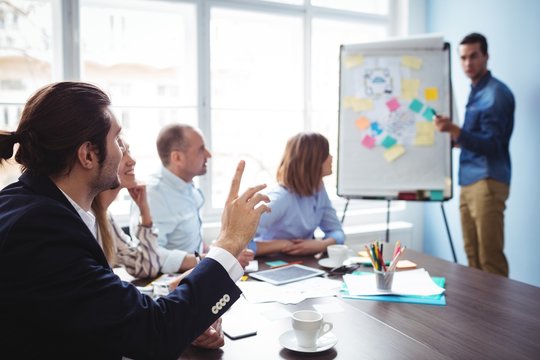 Speaker calling coworker with hand raised during meeting