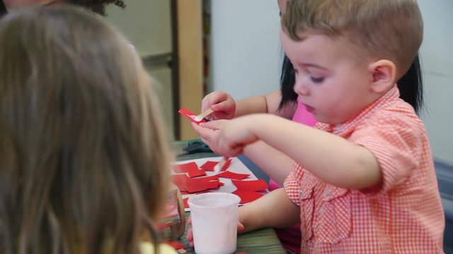 Nursery students doing arts and crafts in the classroom with their teachers.