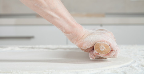 Housewife  flattening a dough with a rolling pin