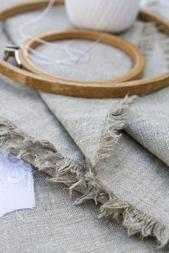 Set for embroidery, garment needle and embroidery hoop on unbleached linen fabric. Selective focus, shallow depth of field