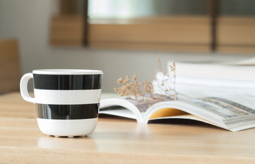 Coffee cup and open book with dried flower on the desk