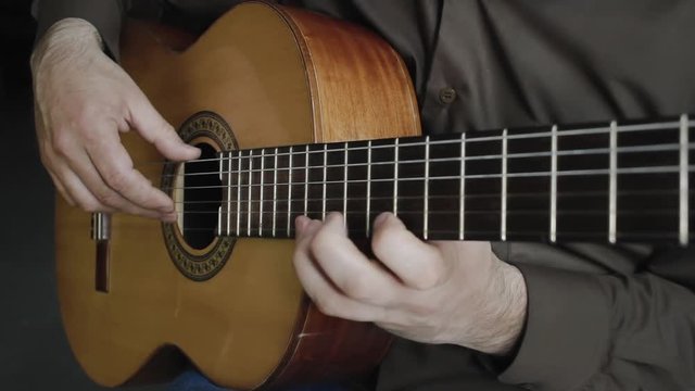 The man plays on a classical acoustic guitar