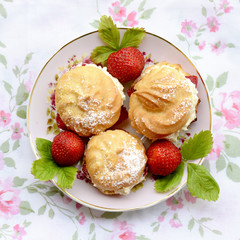 Cream puffs or profiterole filled with whipped cream served with strawberries 
