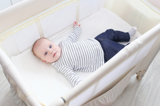 Lovely little 3 months baby lying in travel crib