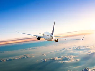 Photo sur Aluminium Avion Avion volant au-dessus des nuages dans un coucher de soleil spectaculaire