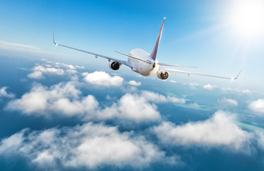 Naklejka na ściany i meble Commercial jet plane flying above clouds