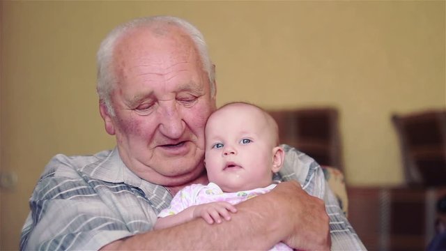 happy grandfather holds a baby on hands and talking