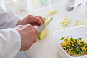 Повар режет яблоко на белой разделочной доске