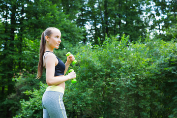 Sport woman doing exercises with dumbbells outdoors.