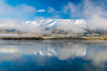Winter morning view of Pisa range (part of the southern alps reflected in lake Dunstan, Cromwell, New Zealand
