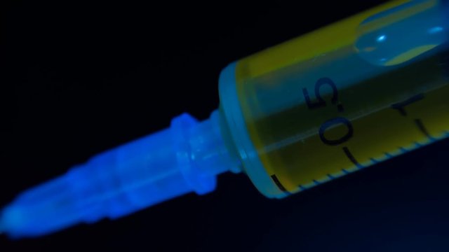 Addict injects heroin or meth by syringe into a vein on black background. Macro