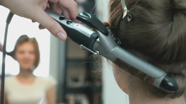 Professional stylist makes the curls to a girl