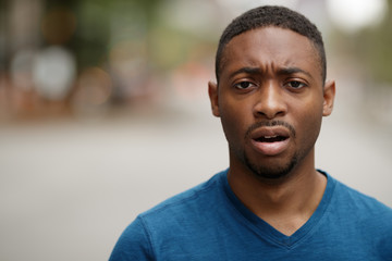 Fototapeta premium Young black man in city shocked face portrait