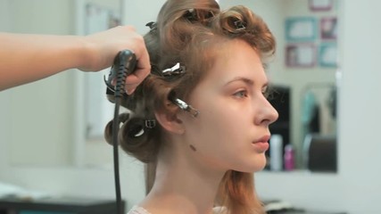 Professional stylist makes the curls to a girl