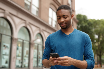 Young man in city texting cell phone