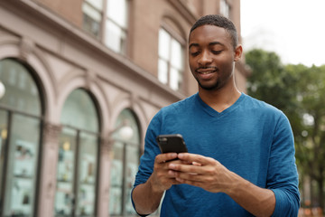Young black African American man in city texting cell phone