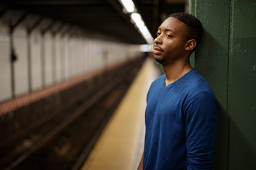 Young man in city at subway platform tired