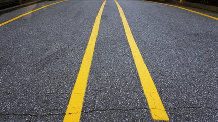 yellow line on street divided between car at parking lot of load
