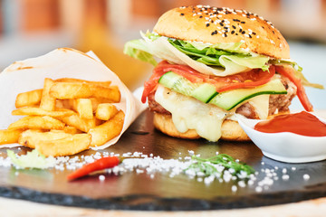 Fast food dinner of Burger, fries and a Cup of sauce, served on a stone Board