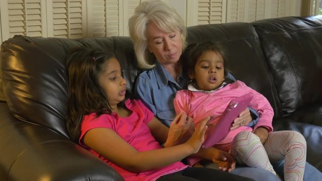 Two young girls teach their adopted grandmother a game on the IPAD.