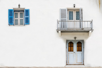 The front of the house with a white wall with doors, windows and balconies.