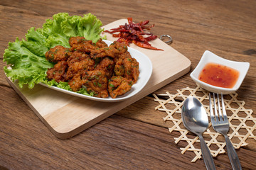 Thai fried fish cake (Tod Mun Pla) or prawn fritter ball serve with red sauce Thai traditional food recipe isolated on wood background