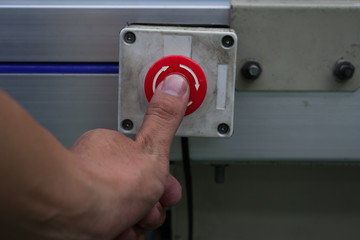 Male hand pushing emergency red stop button.