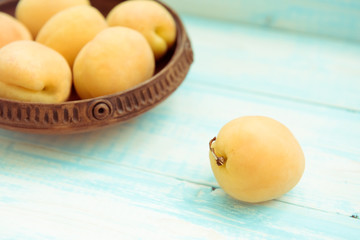 Fresh ripe apricots in vintage bowl on turquoise wooden background