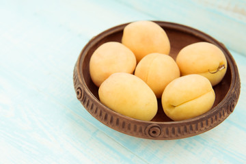 Fresh ripe apricots in vintage bowl on turquoise wooden background