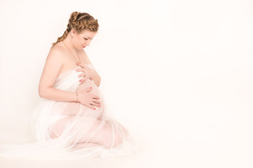 Happy pregnant woman sitting on white background