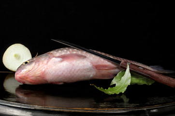 Raw fish on a black background and antique wooden surface.