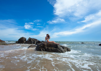 Fototapeta na wymiar Woman on the rock in ocean