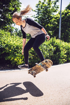 Skateboarder woman practicing ollie at park