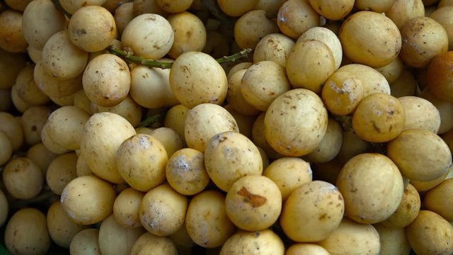 FullHD video - Small, round, sweet lanzones fruit, still clustered on their stems, displayed for sale at an outdoor public market in Asia.